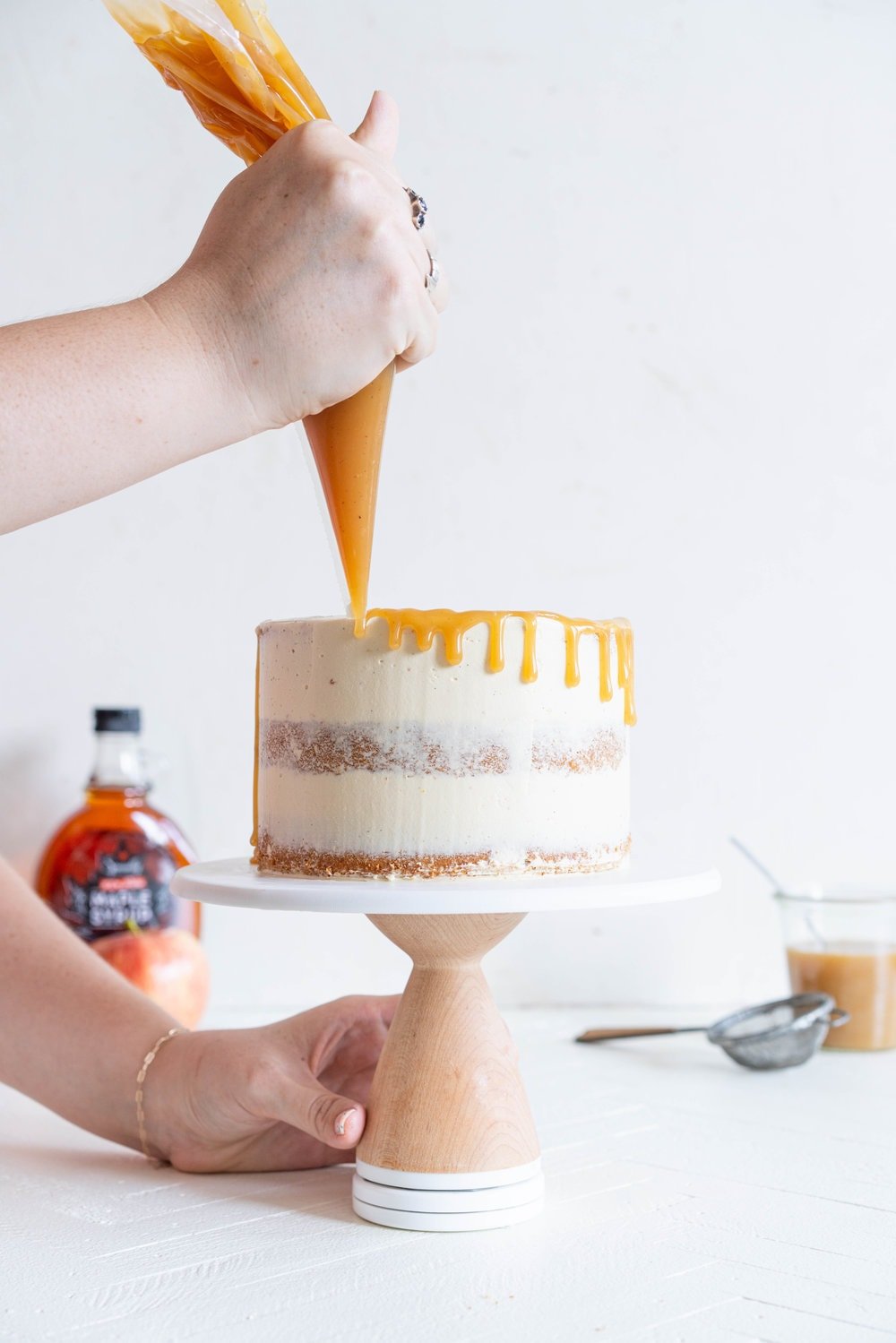 Spiced Brown Sugar cake with Cinnamon Apple Filling and Maple Caramel German Buttercream. This layer cake screams fall - a cozy brown sugar spice cake is layered with a cinnamon apple filling and a maple caramel german buttercream, then finished with a maple salted caramel drizzle and a dusting of cinnamon. This is the perfect fall inspired layer cake #autumncake #applecake #layercake
