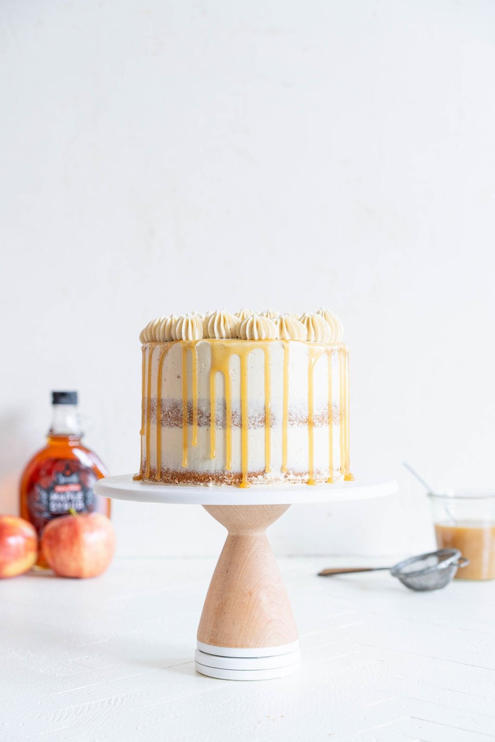 Spiced Brown Sugar cake with Cinnamon Apple Filling and Maple Caramel German Buttercream. This layer cake screams fall - a cozy brown sugar spice cake is layered with a cinnamon apple filling and a maple caramel german buttercream, then finished with a maple salted caramel drizzle and a dusting of cinnamon. This is the perfect fall inspired layer cake #autumncake #applecake #layercake