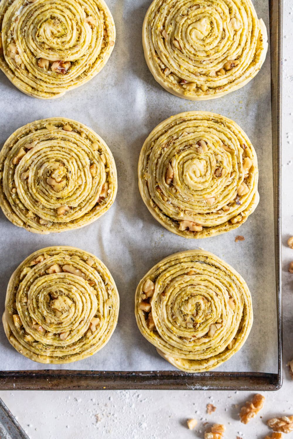 Laminated Brioche Pesto Buns with Lemon, Parmesan, and Walnut - buttery brioche is layered with zesty lemon, basil pesto and cheese, then sprinkled with walnuts and rolled up in to perfect pesto brioche pinwheel rolls. These are the perfect savoury take on a traditional laminated brioche #briocherolls #pestorolls #laminatedbrioche
