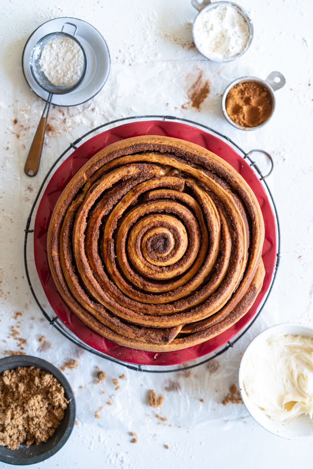 Giant Sour Cream Brioche Cinnamon Roll with Cream Cheese Frosting. A huge cinnamon roll, made from soft, pillowy brioche enriched with sour cream, is spread with a cinnamon sugar mixture and rolled up into a giant cinnamon roll which is baked until perfect and fluffy. It is then finished with a simple cream cheese frosting. This is the perfect holiday breakfast or brunch treat! #giantcinnamonroll #sourcreambrioche #creamcheesefrosting