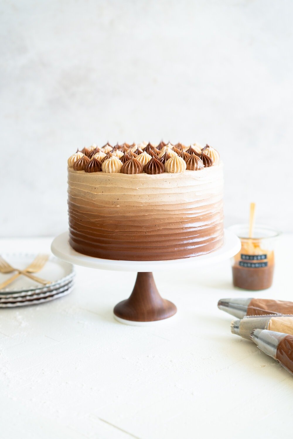 Apple Cider Layer Cake with Spiced Caramel Swiss Meringue Buttercream. This layer cake has reduced apple cider added to the batter, giving it a delicate apple flavour. It is finished with spiced salted caramel swiss meringue buttercream with an ombre finish.  #applecidercake #caramelbuttercream #swissmeringue