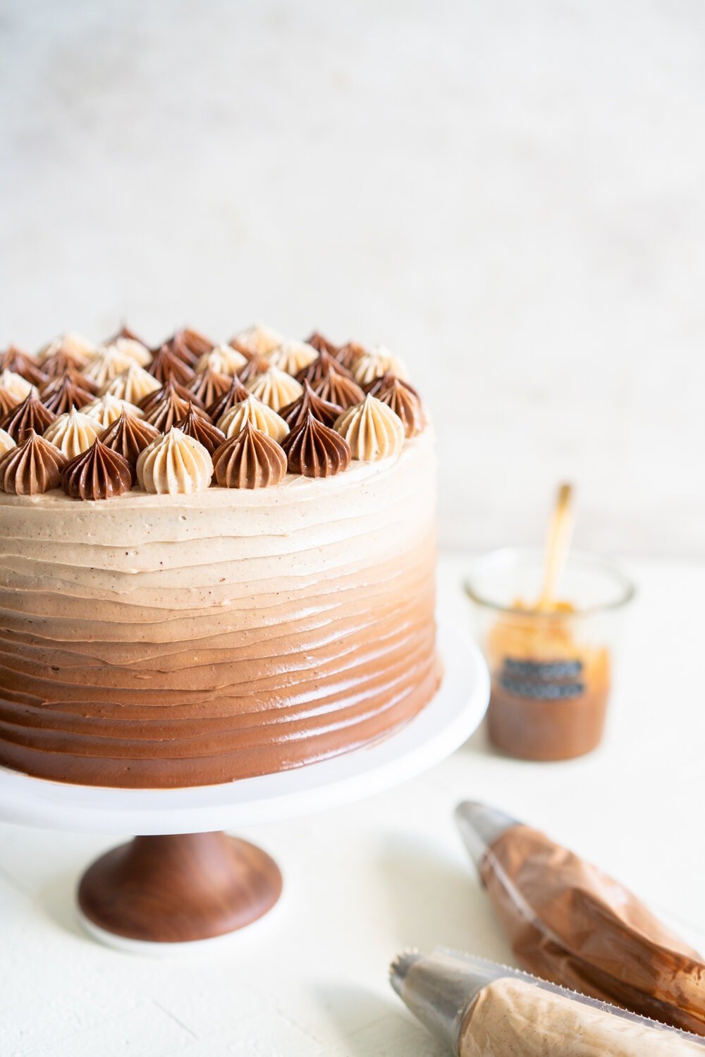 Apple Cider Layer Cake with Spiced Caramel Swiss Meringue Buttercream. This layer cake has reduced apple cider added to the batter, giving it a delicate apple flavour. It is finished with spiced salted caramel swiss meringue buttercream with an ombre finish.  #applecidercake #caramelbuttercream #swissmeringue