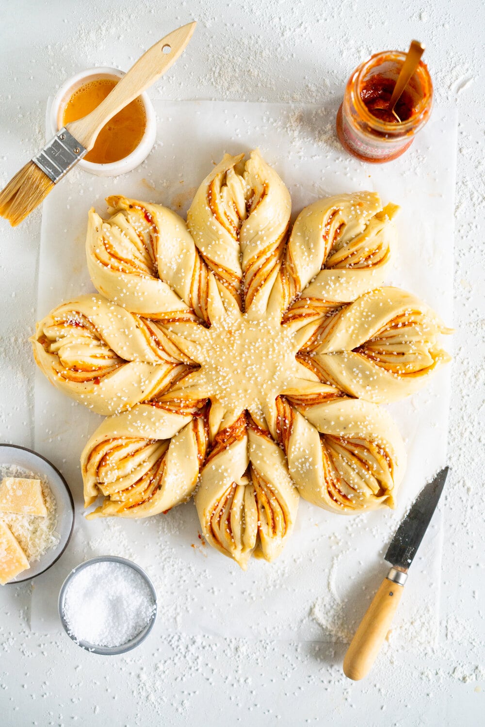 Spicy Tomato Pesto and Parmesan Star Bread. Brioche dough is layered with spicy tomato pesto and parmesan, then twisted into an easy but beautiful star bread which is perfect for tearing and sharing.