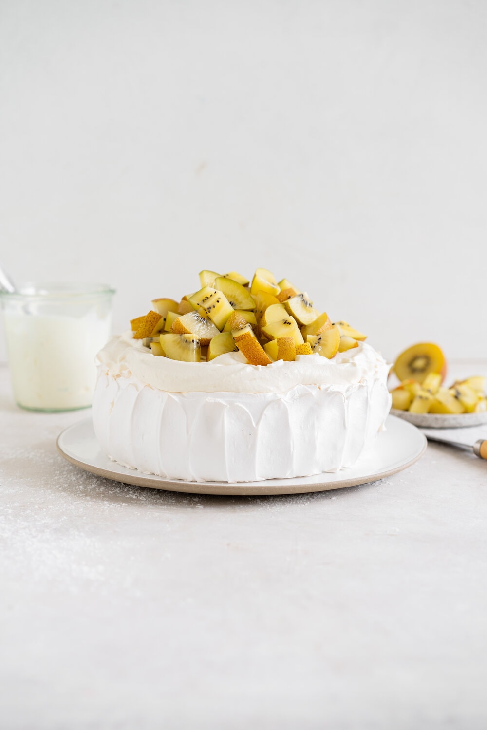 The most perfect, easy pavlova recipe. Using Swiss Meringue instead of the traditional French, this pavlova recipe is crispy on the outside and has a perfect, full, marshmallow center, and is much more stable so is resistant to humidity and changes in weather. It is easy to make and the perfect crowd pleaser. This is the most perfect year round dessert. Topped with Manuka Honey whipped cream and golden kiwifruit, this is a New Zealand classic.