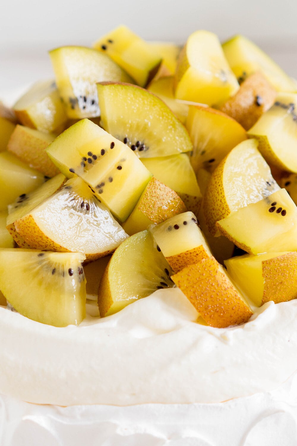 The most perfect, easy pavlova recipe. Using Swiss Meringue instead of the traditional French, this pavlova recipe is crispy on the outside and has a perfect, full, marshmallow center, and is much more stable so is resistant to humidity and changes in weather. It is easy to make and the perfect crowd pleaser. This is the most perfect year round dessert. Topped with Manuka Honey whipped cream and golden kiwifruit, this is a New Zealand classic.