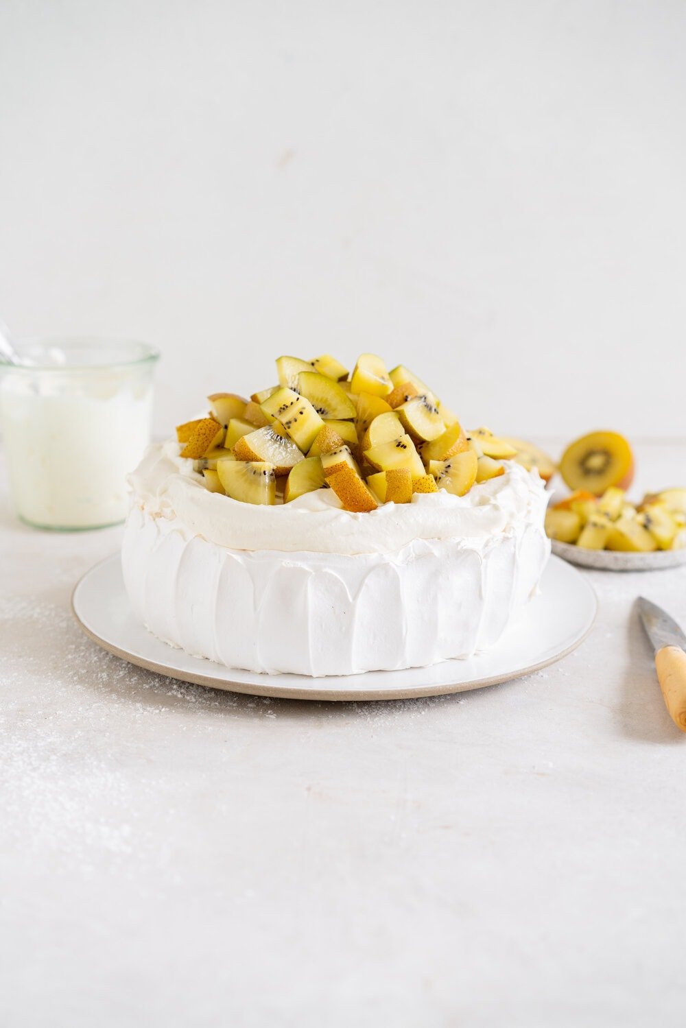 The most perfect, easy pavlova recipe. Using Swiss Meringue instead of the traditional French, this pavlova recipe is crispy on the outside and has a perfect, full, marshmallow center, and is much more stable so is resistant to humidity and changes in weather. It is easy to make and the perfect crowd pleaser. This is the most perfect year round dessert. Topped with Manuka Honey whipped cream and golden kiwifruit, this is a New Zealand classic.