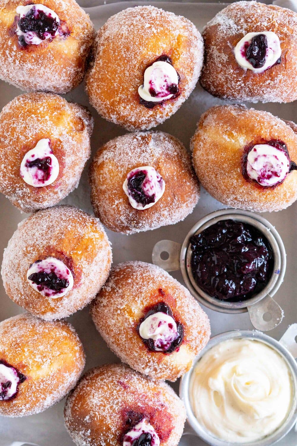 Fluffy doughnuts are fried until perfectly golden brown, then coated in sugar and filled with a whipped vanilla bean cheesecake filling and a balsamic blueberry compote. These are the most perfect treat!