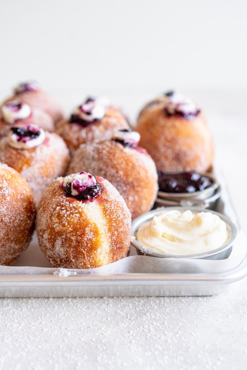 Fluffy doughnuts are fried until perfectly golden brown, then coated in sugar and filled with a whipped vanilla bean cheesecake filling and a balsamic blueberry compote. These are the most perfect treat!