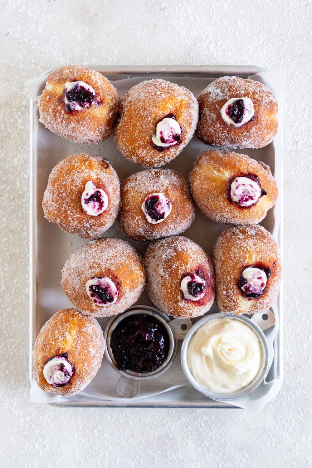 Fluffy doughnuts are fried until perfectly golden brown, then coated in sugar and filled with a whipped vanilla bean cheesecake filling and a balsamic blueberry compote. These are the most perfect treat!