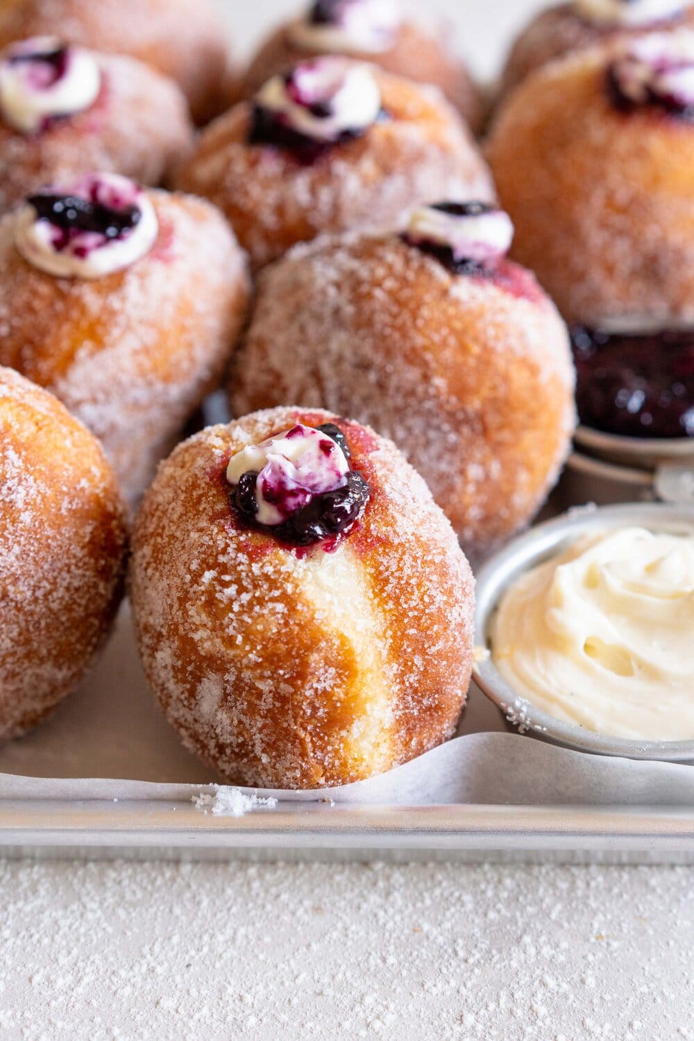 Fluffy doughnuts are fried until perfectly golden brown, then coated in sugar and filled with a whipped vanilla bean cheesecake filling and a balsamic blueberry compote. These are the most perfect treat!
