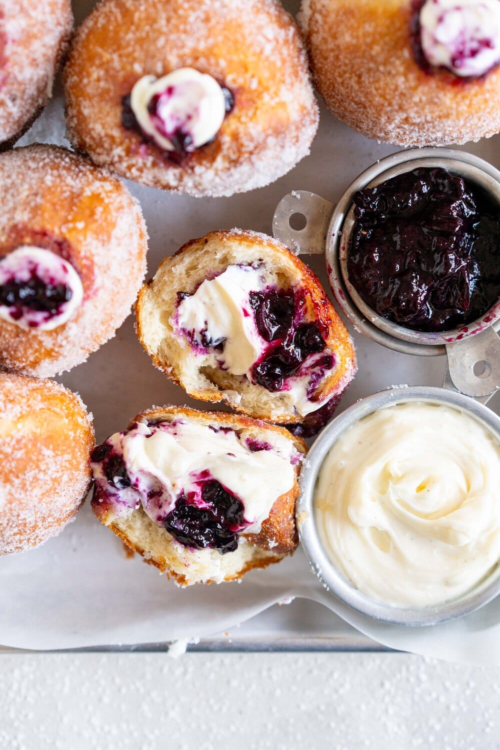 Fluffy doughnuts are fried until perfectly golden brown, then coated in sugar and filled with a whipped vanilla bean cheesecake filling and a balsamic blueberry compote. These are the most perfect treat!