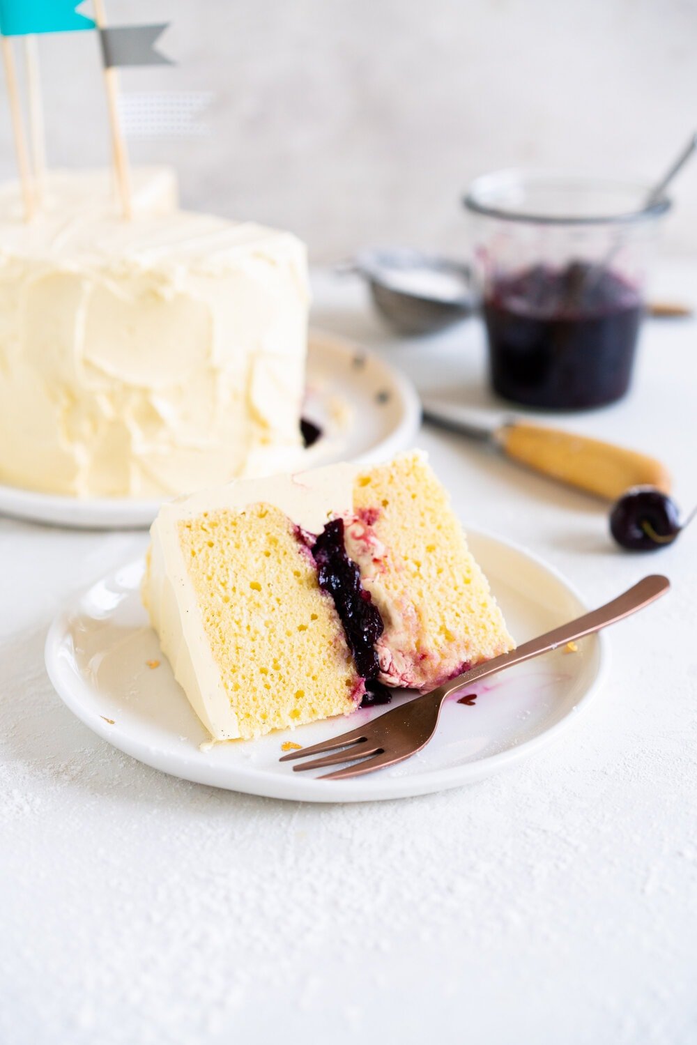 Two Layer Vanilla Bean Buttermilk Cake with Cherry Compote and Vanilla Bean Swiss Meringue Buttercream. This small two-layer cake is perfect for a celebration with a small group. The cake is tender from the reverse creaming method, and the Swiss meringue buttercream is smooth and silky. This is the perfect vanilla bean cake!