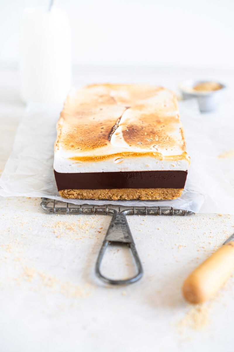 S'mores Bars on wire rack with layer of toasted marshmallow on top.