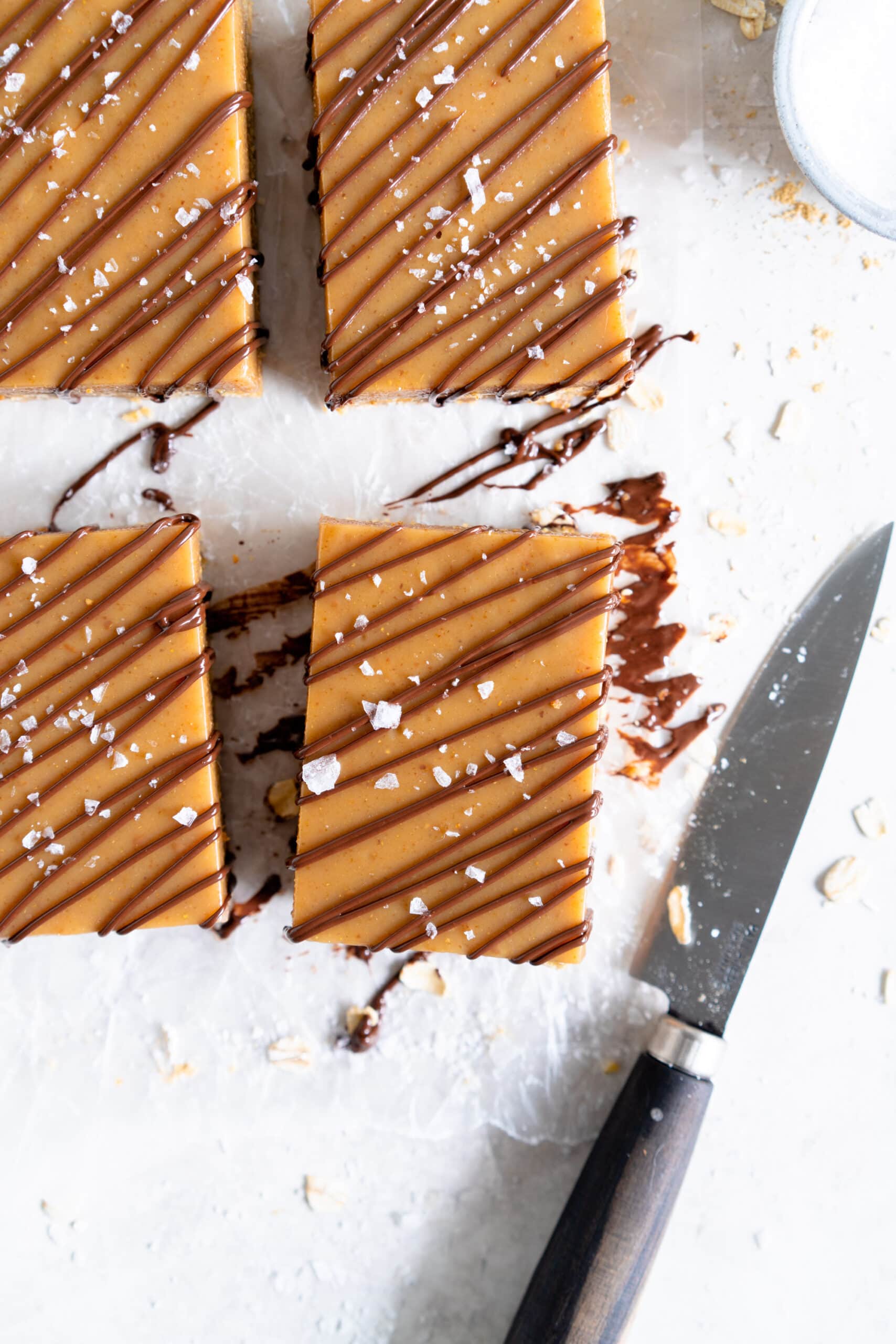 corner shot of ginger caramel slice drizzled with chocolate and flaky sea salt.