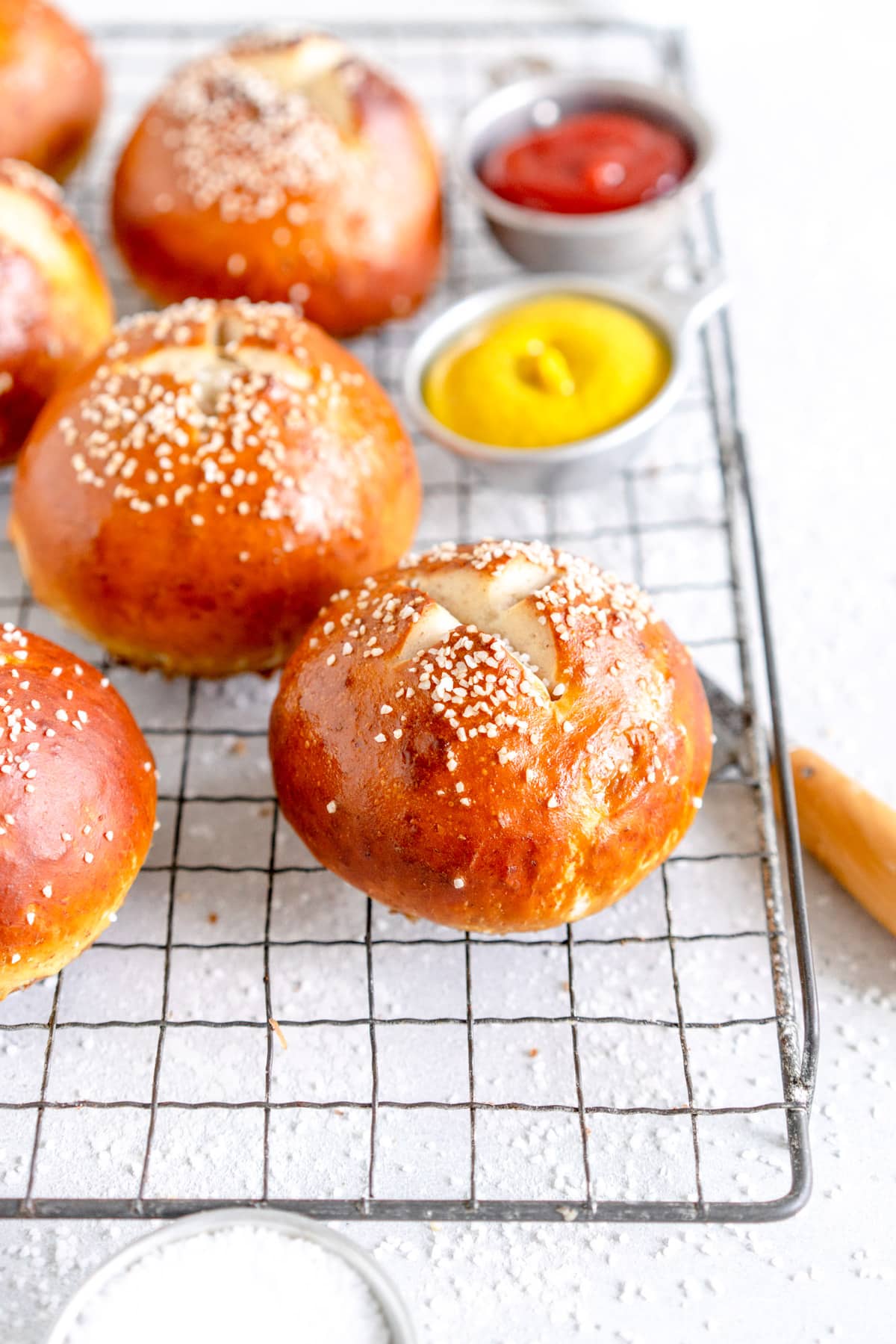 side shot of pretzel bun with salt on a wire cooling rack