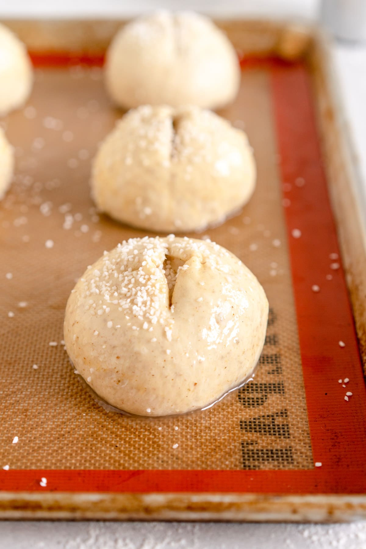 scored bun with salt on the top ready to bake