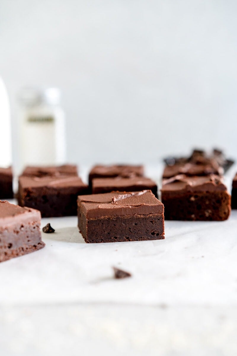 Fudgy brownies on wax paper with frosting