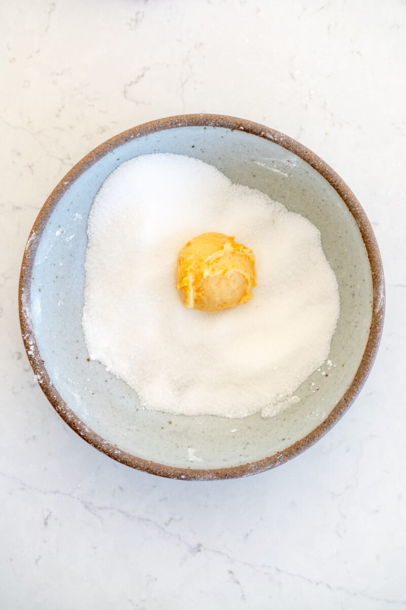 rolling cookie dough in granulated sugar